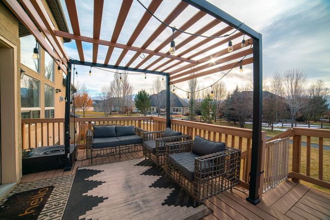 A deck with a pergola and a couch and chairs on it.