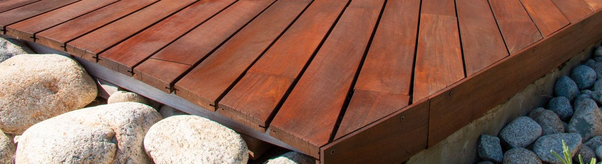 A wooden deck with a circular design is surrounded by rocks.