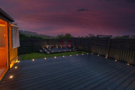 A wooden deck with lights on it is lit up at night.