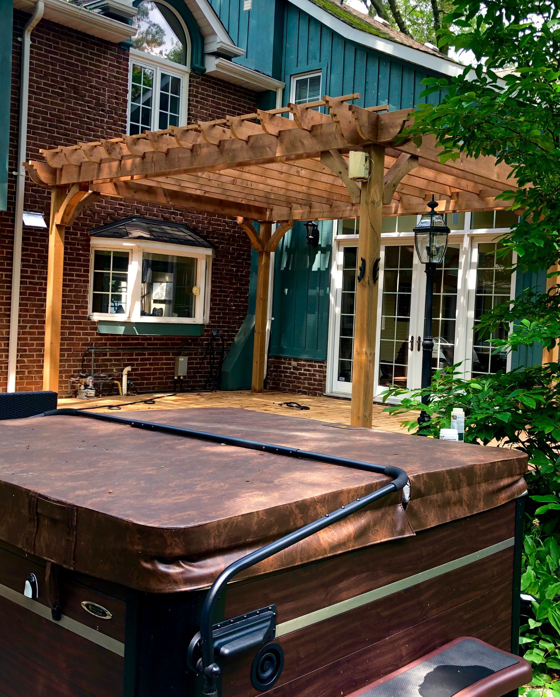 A hot tub is sitting under a pergola in front of a house.