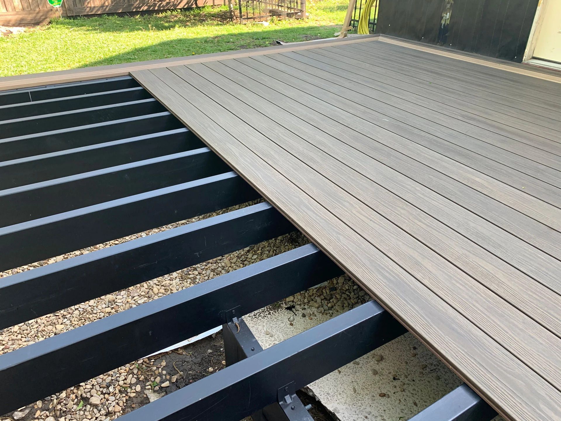 Composite deck being constructed on a black metal frame.