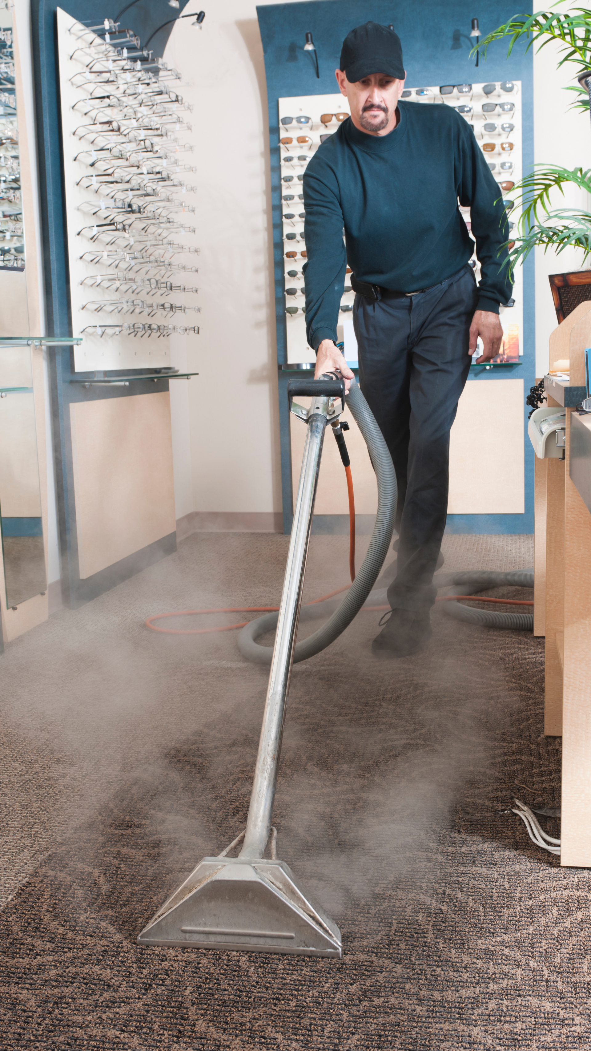 A man is using a vacuum cleaner to clean a carpet in a store.