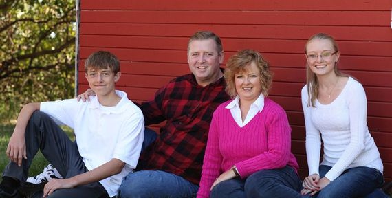 A family is posing for a picture in front of a red barn.