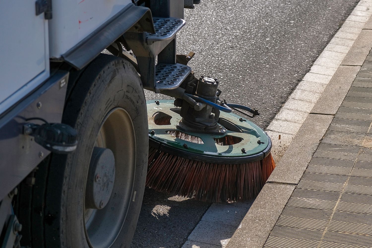 Street sweeper cleaning a sidewalk, showing the brush and wheel. Street sweeper cleaning a sidewalk, showing the brush and wheel.
