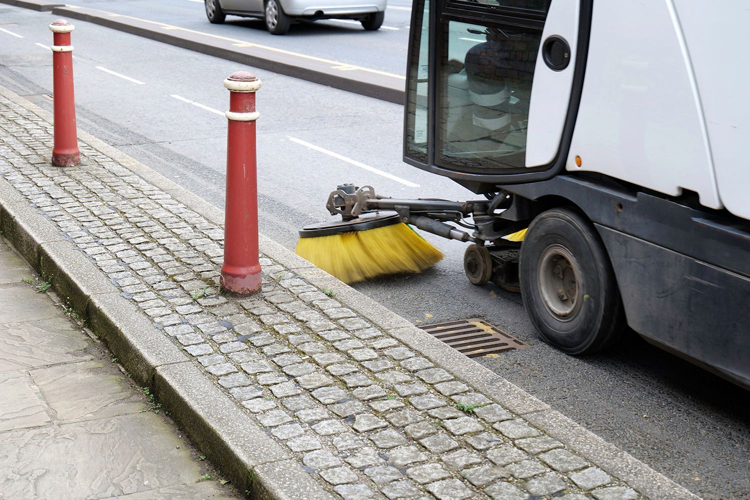 Street sweeper cleaning a road, dust and debris visible. Street sweeper cleaning a road, dust and debris visible.