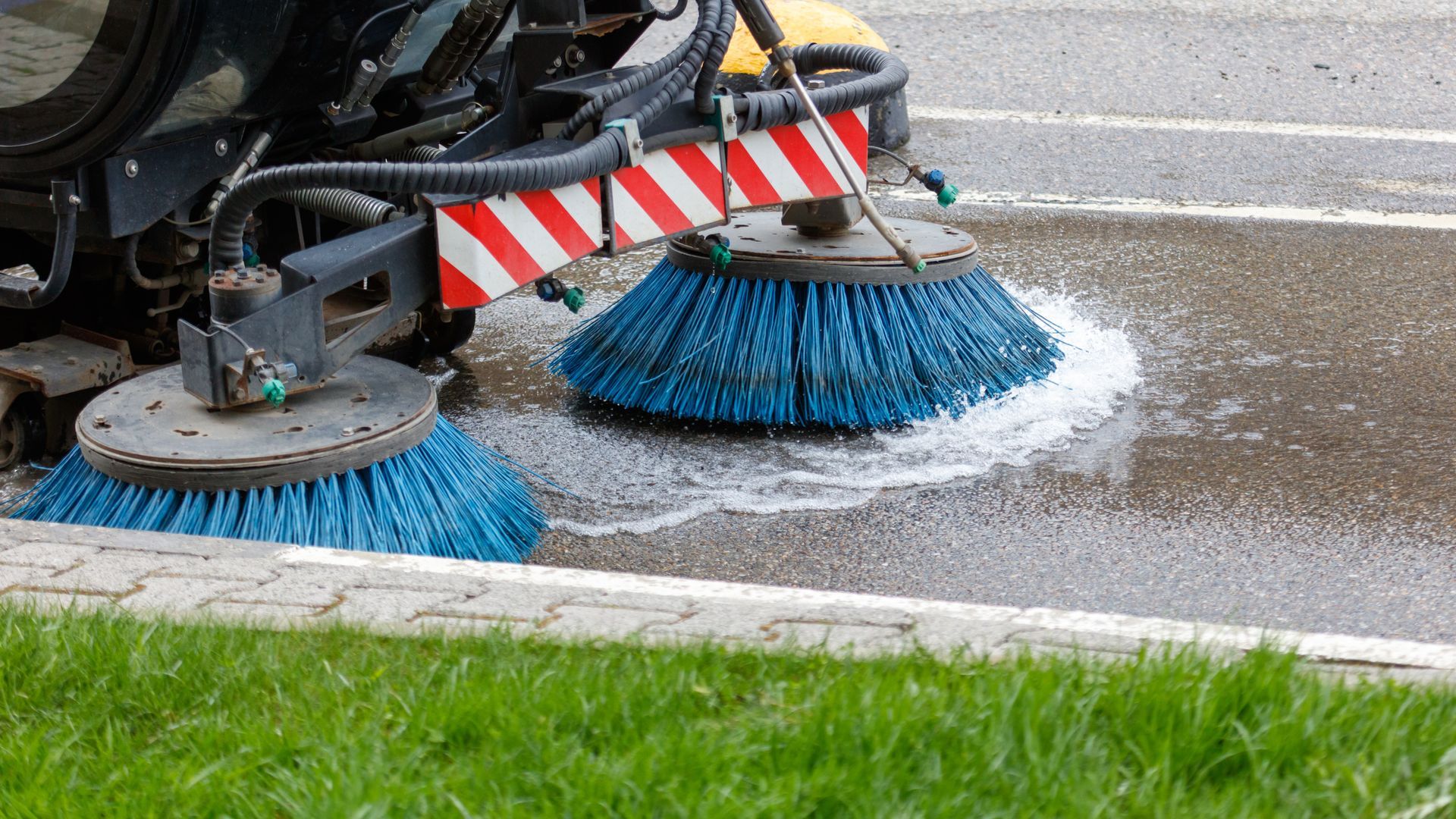 A street sweeper machine cleaning leaves from a roadside. A street sweeper machine cleaning leaves from a roadside.