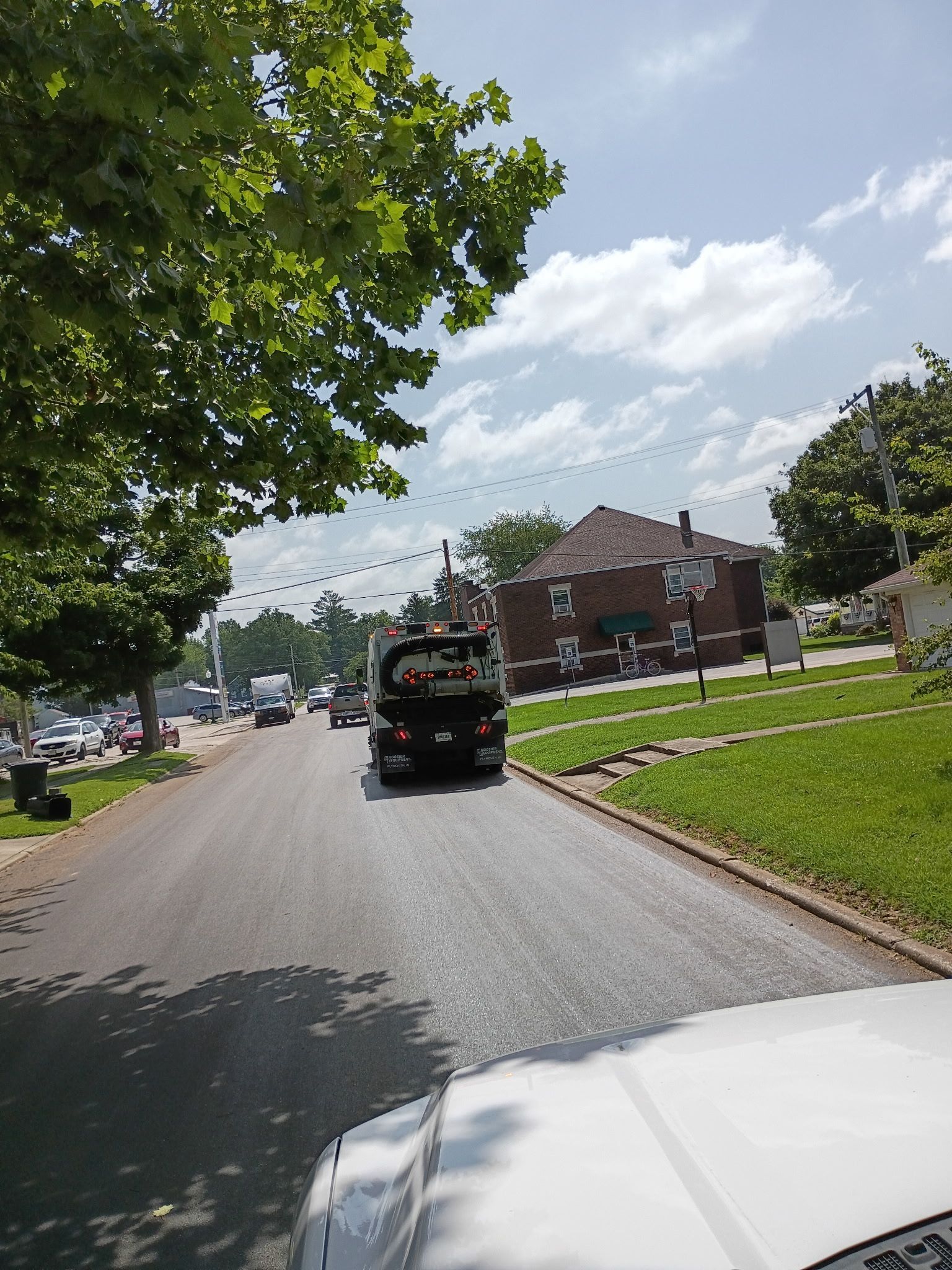 Orange street sweeper, front detail, sweeping asphalt, outdoor.