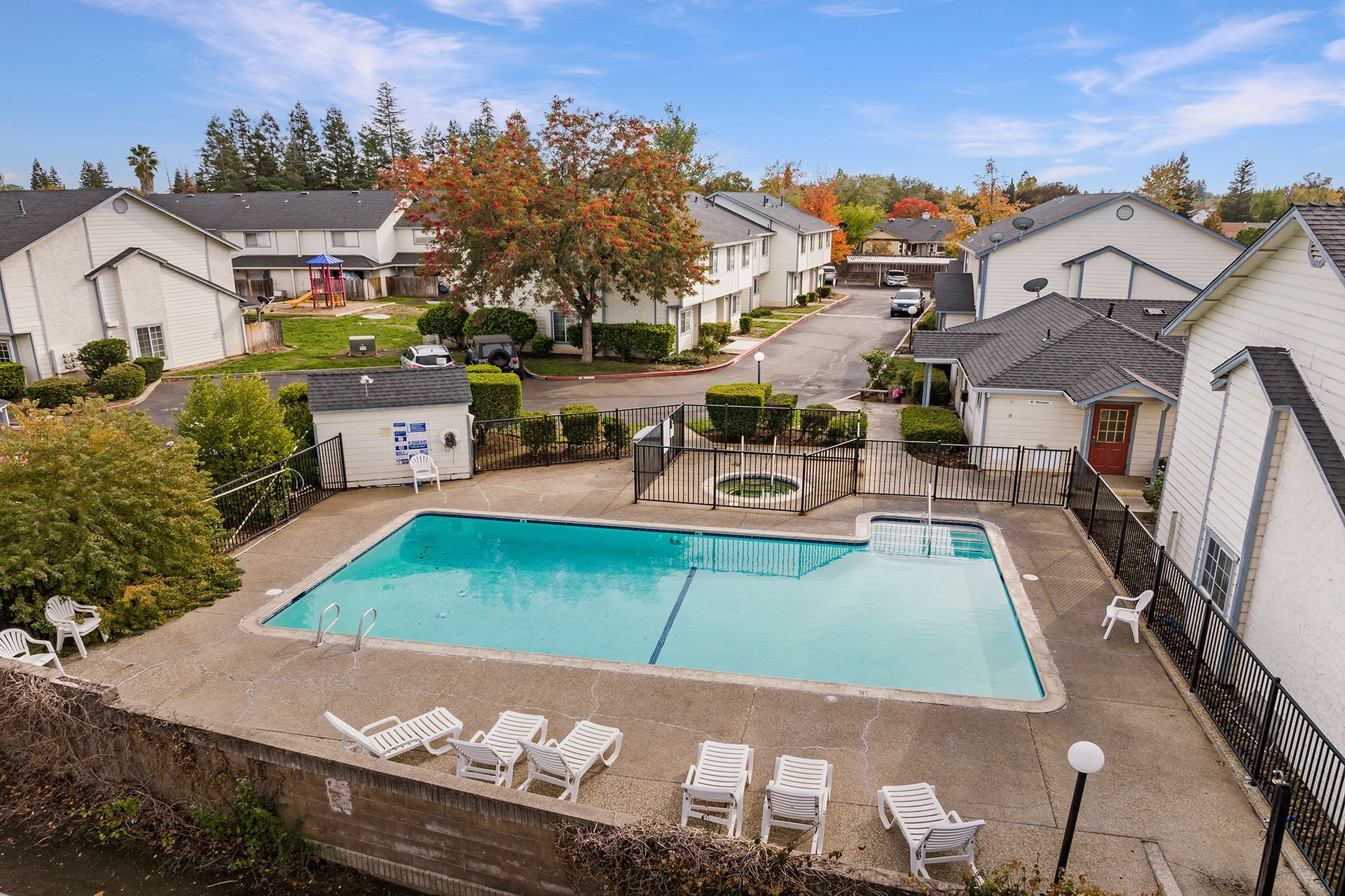 An aerial view of a swimming pool in a residential area surrounded by houses.