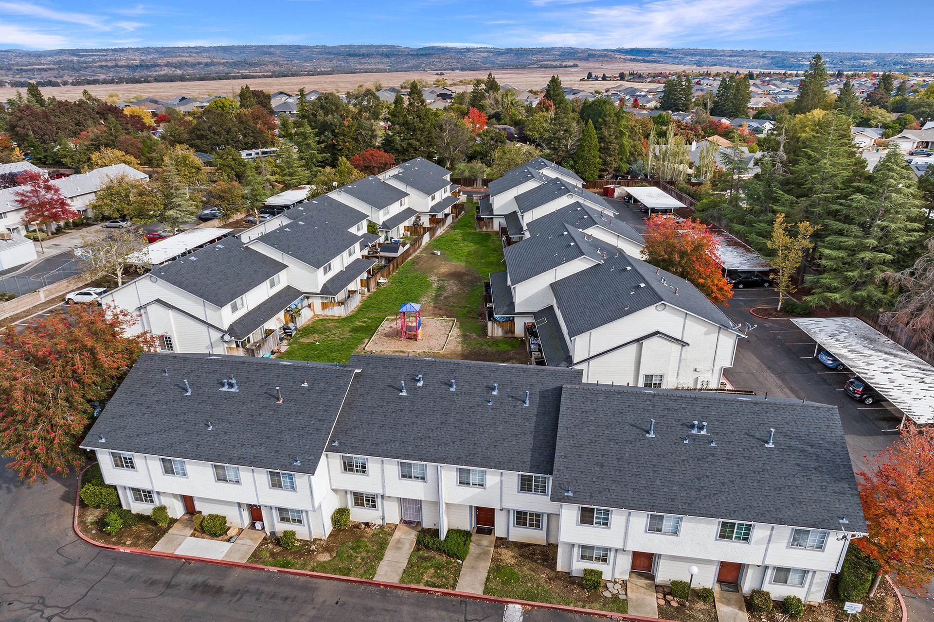 An aerial view of a row of apartment buildings with trees in the background.
