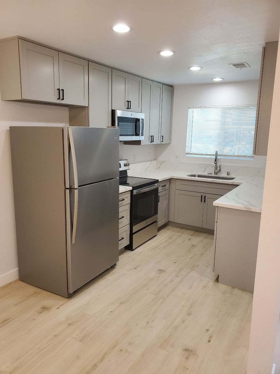 A kitchen with a refrigerator , stove , microwave and sink.