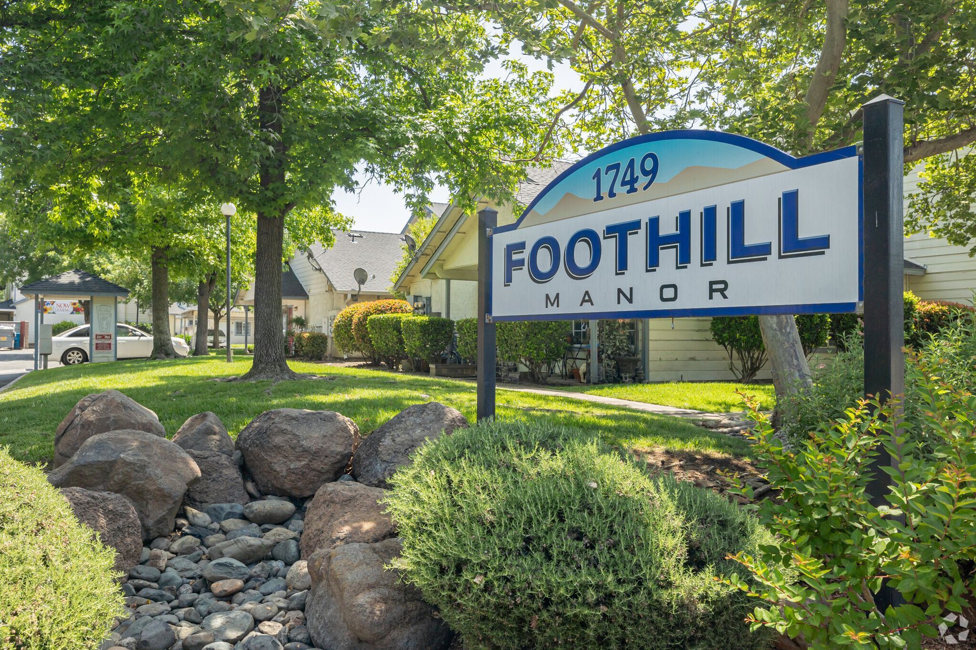 A sign for foothill manor is in front of a house