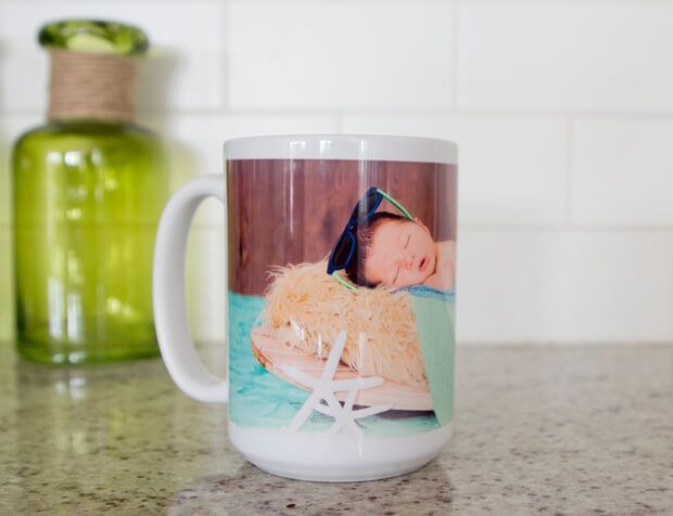 A coffee mug with a picture of a baby on it is sitting on a counter.