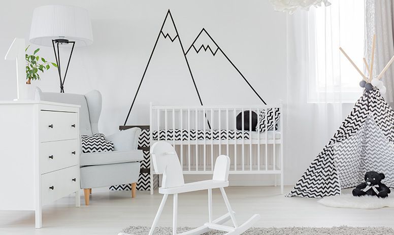 A black and white nursery with a rocking horse , crib , chair , dresser and teepee.