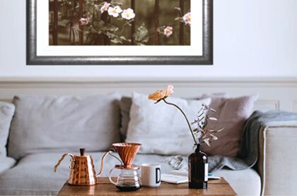 A living room with a couch and a table with a vase of flowers on it.