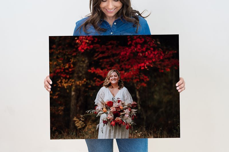 A woman is holding a large canvas with a picture of a woman holding a bouquet of flowers.