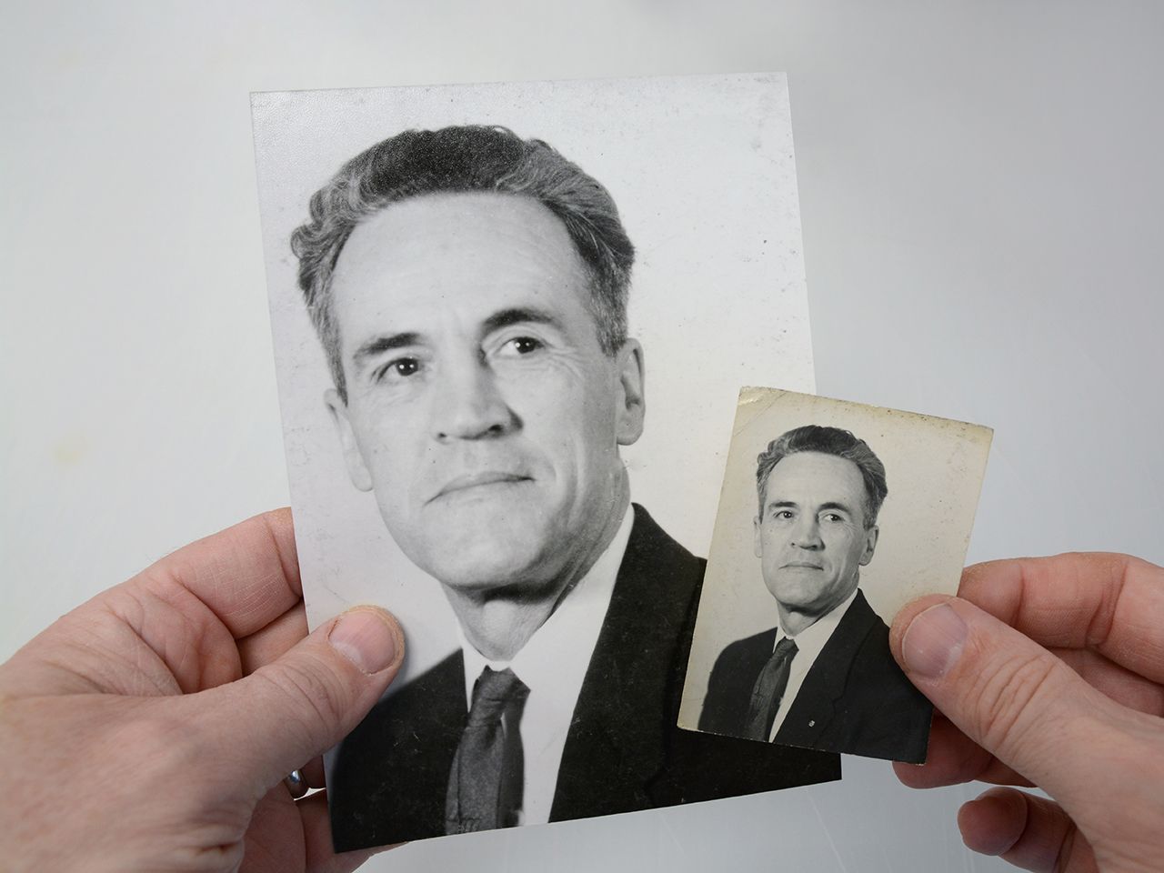 A person is holding a black and white photo of a man in a suit and tie