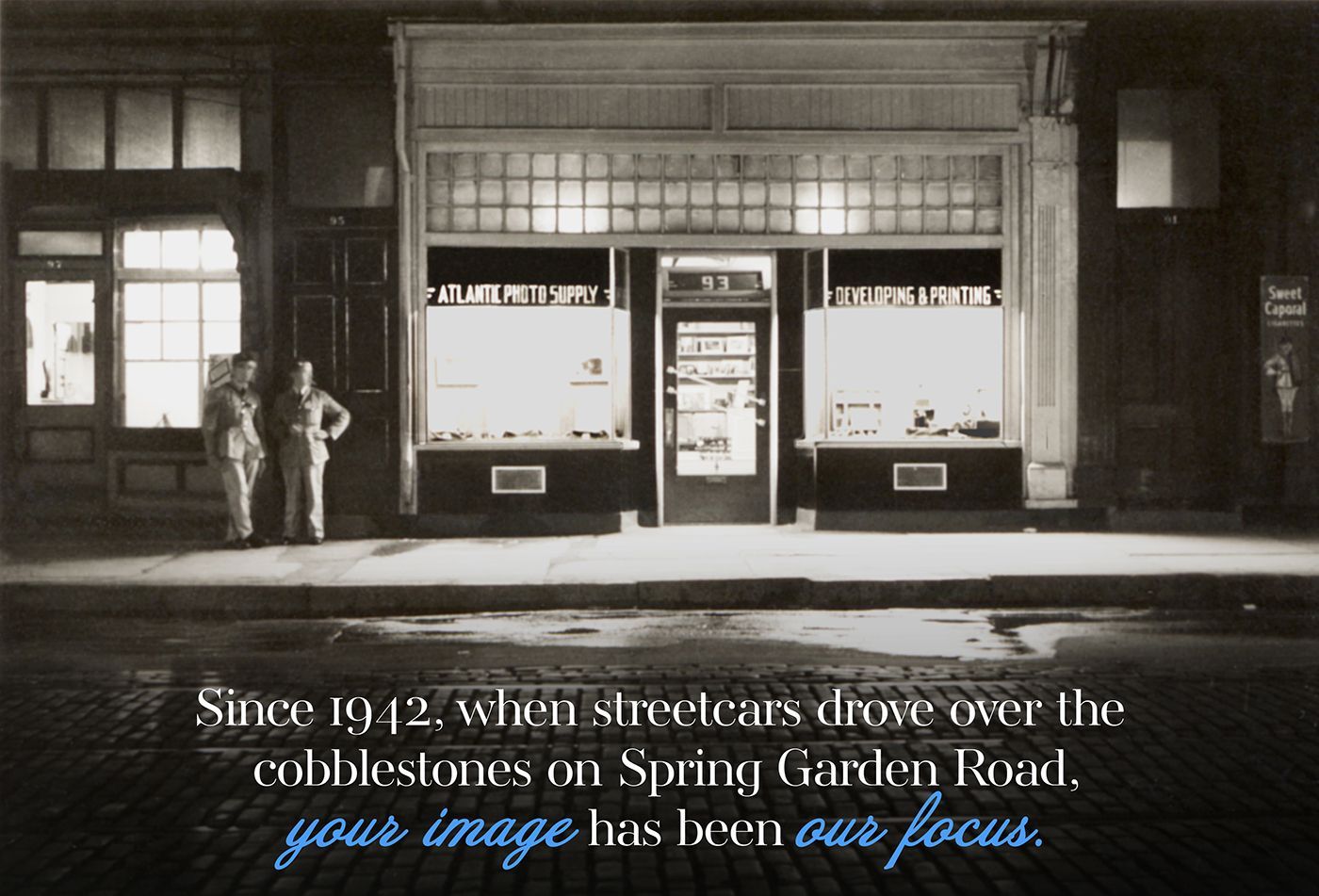 A black and white photo of two men standing in front of a store