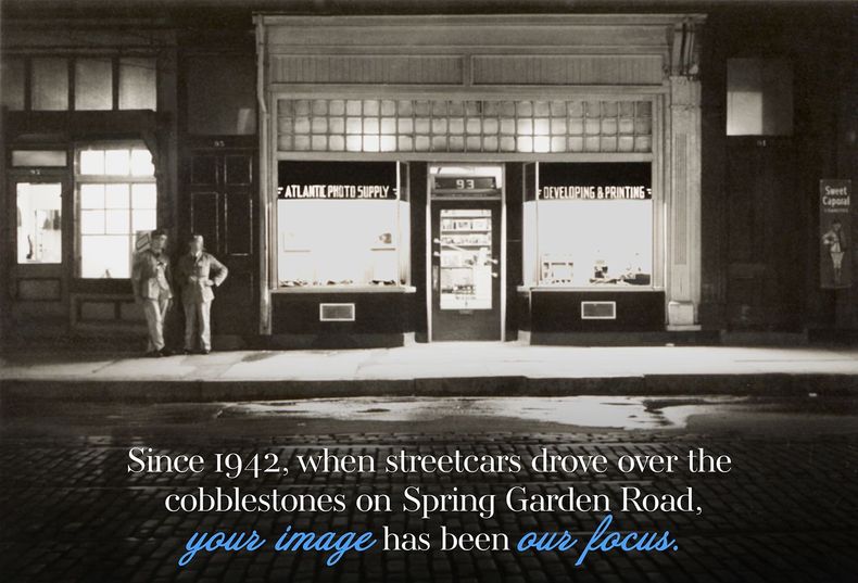 A black and white photo of two men standing in front of a store