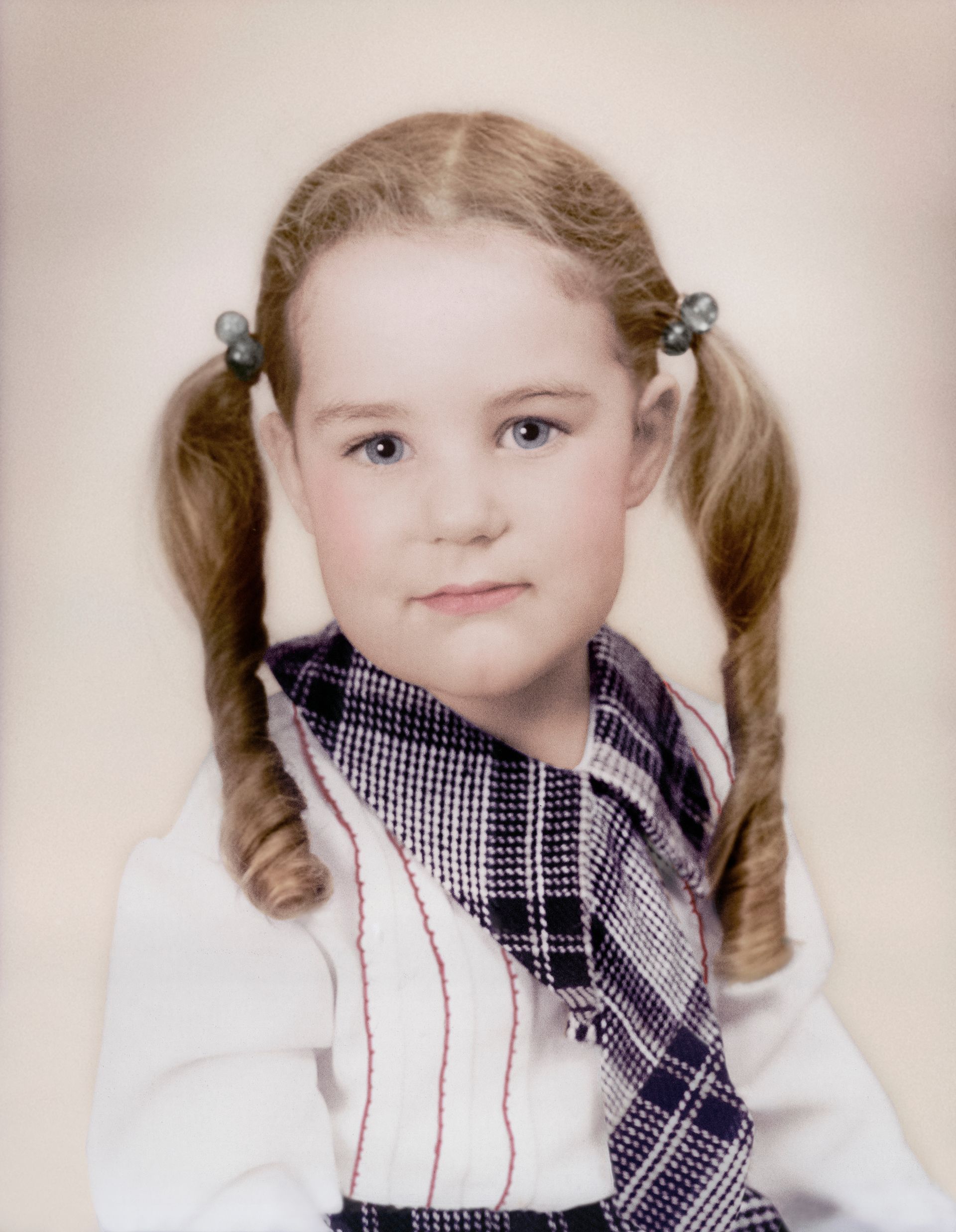 A restored photo of a young girl with pigtails and wearing a plaid shirt and tie.