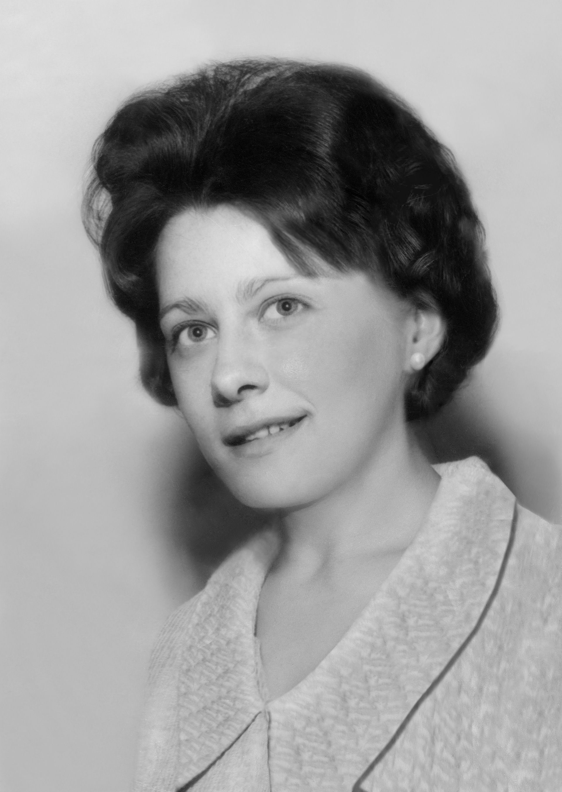 A restored old black and white photo of a woman in a white collared shirt.