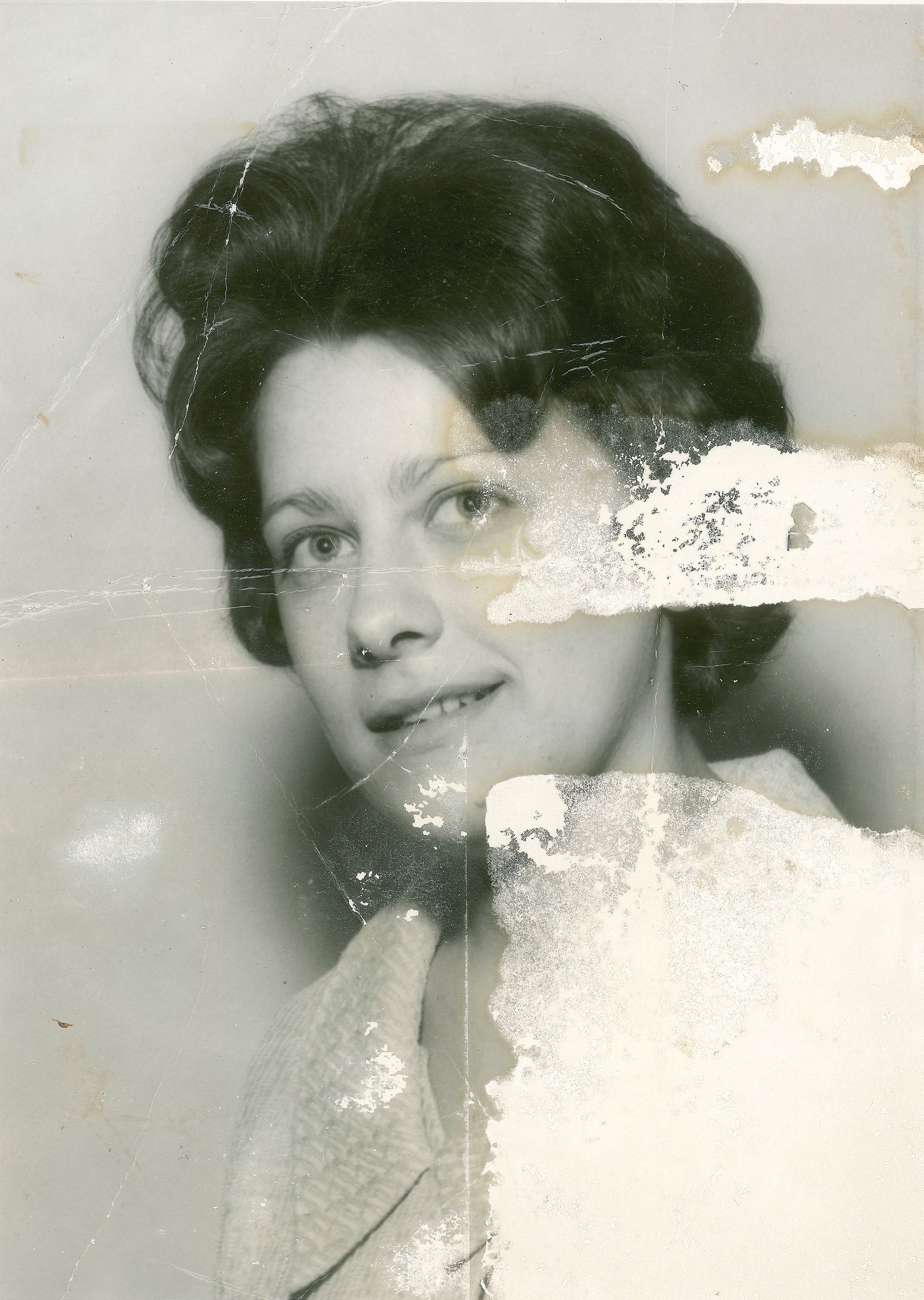 An old black and white photo of a woman in a white collared shirt with a slight stain on her face.