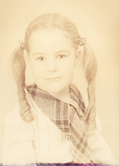 A young girl with pigtails is wearing a plaid shirt and tie.