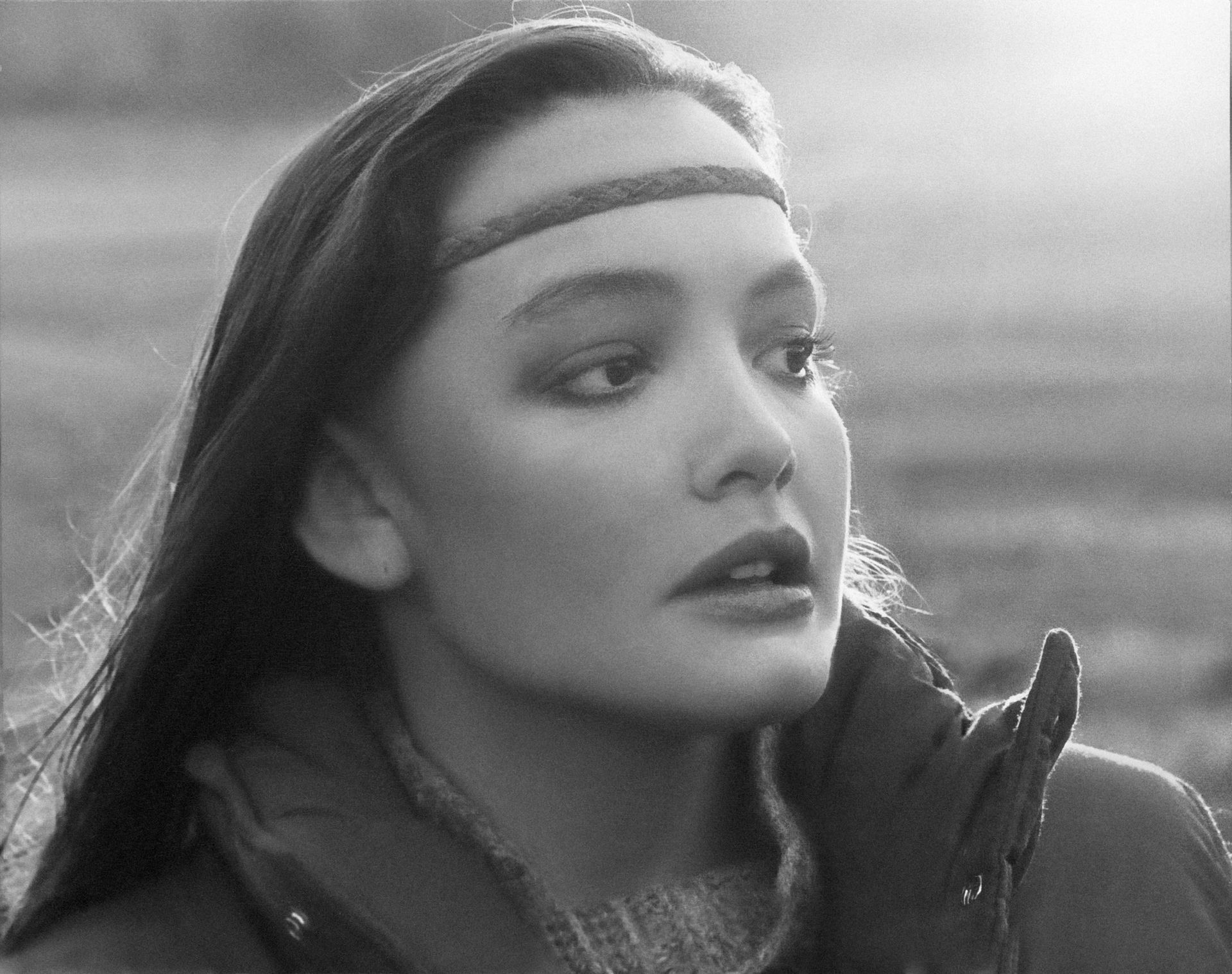 A restored black and white photo of a woman with a headband on her head.