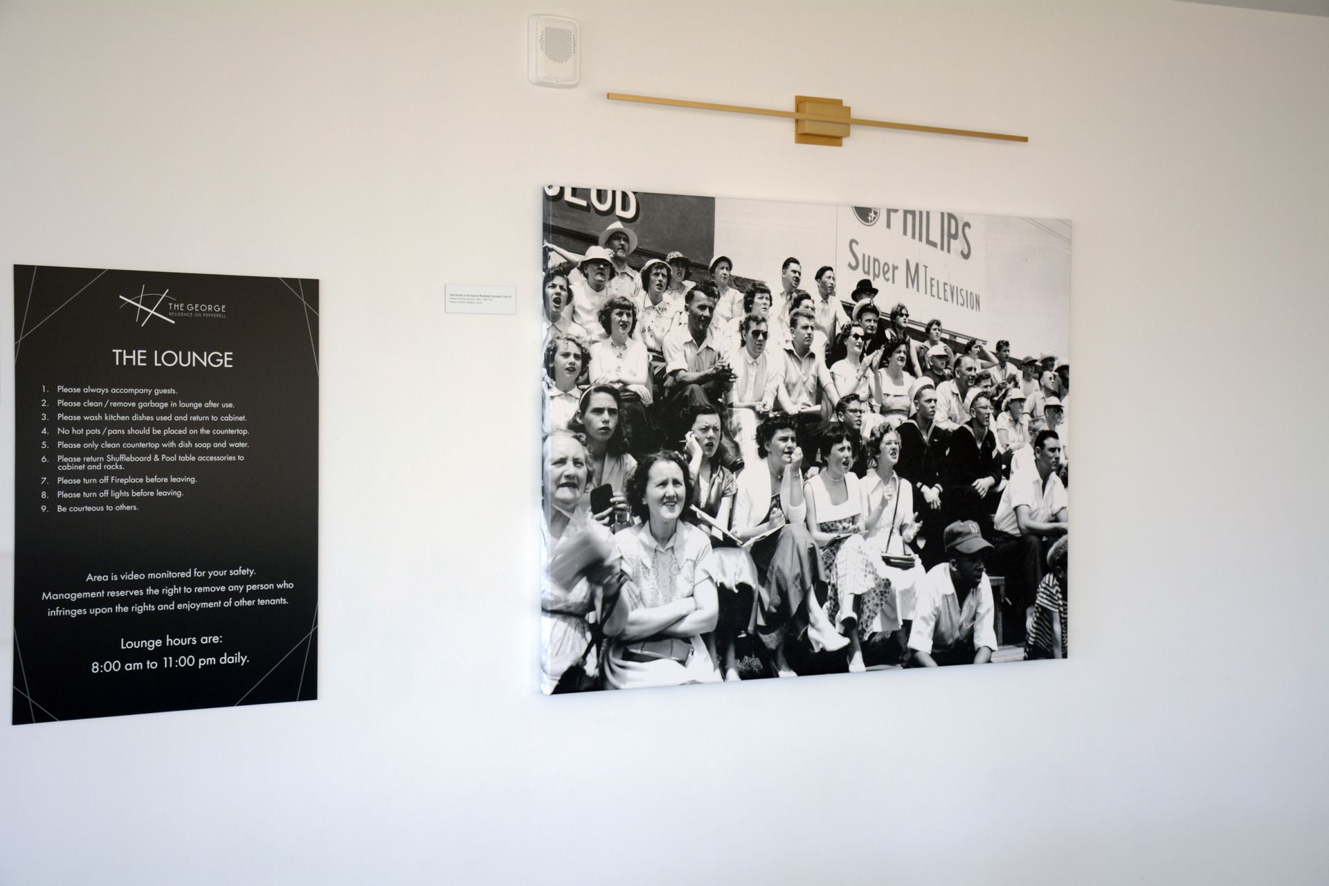 A black and white photo of a group of people is hanging on a wall.