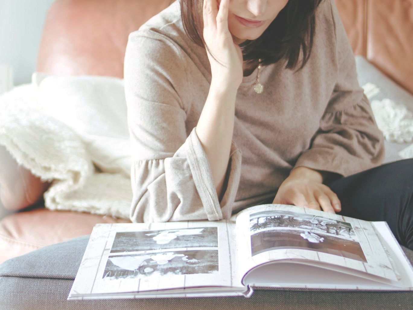 A woman is sitting on a couch reading a book.