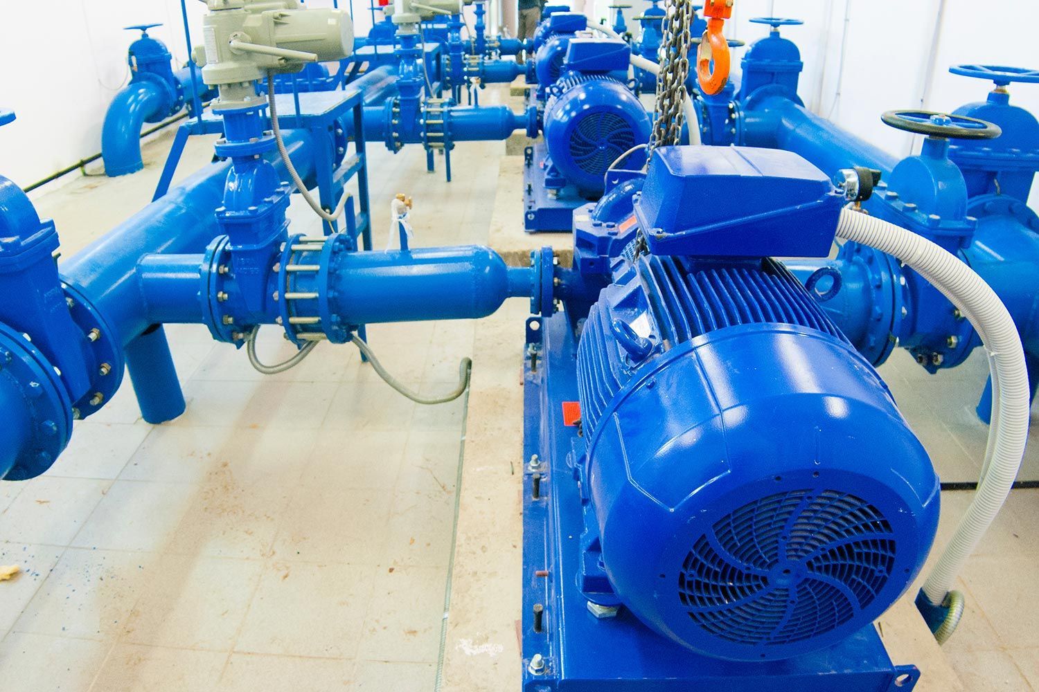 Blue industrial pumps and piping in a mechanical room