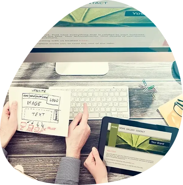 A person is holding a tablet in front of a computer