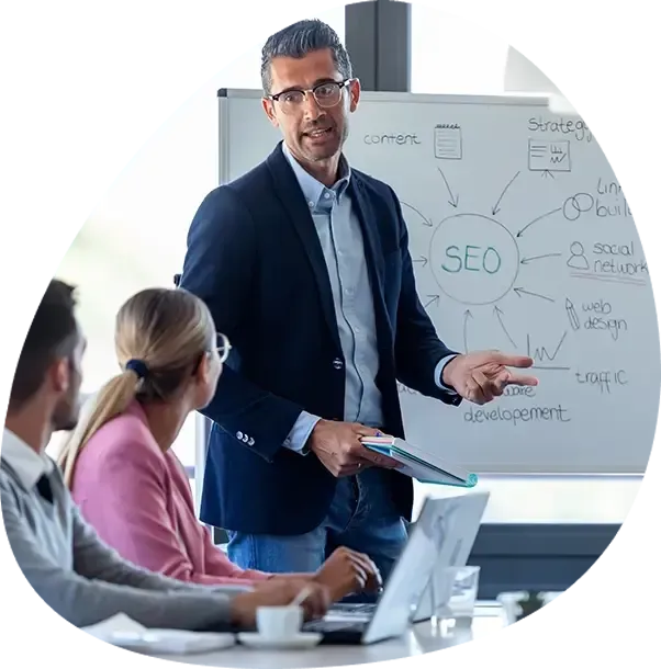 A man is giving a presentation in front of a white board that says seo