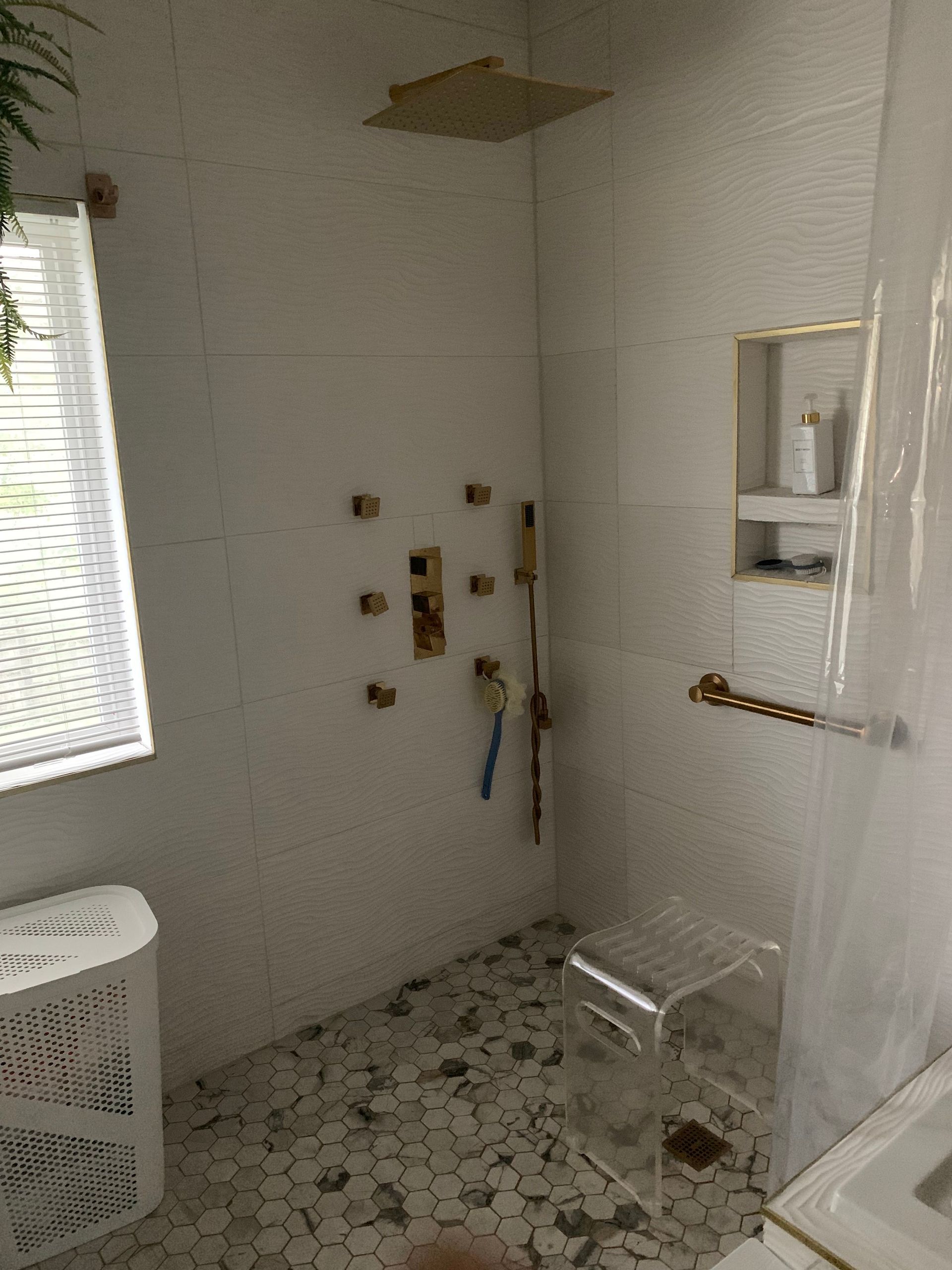 A bathroom with a walk in shower and a window.
