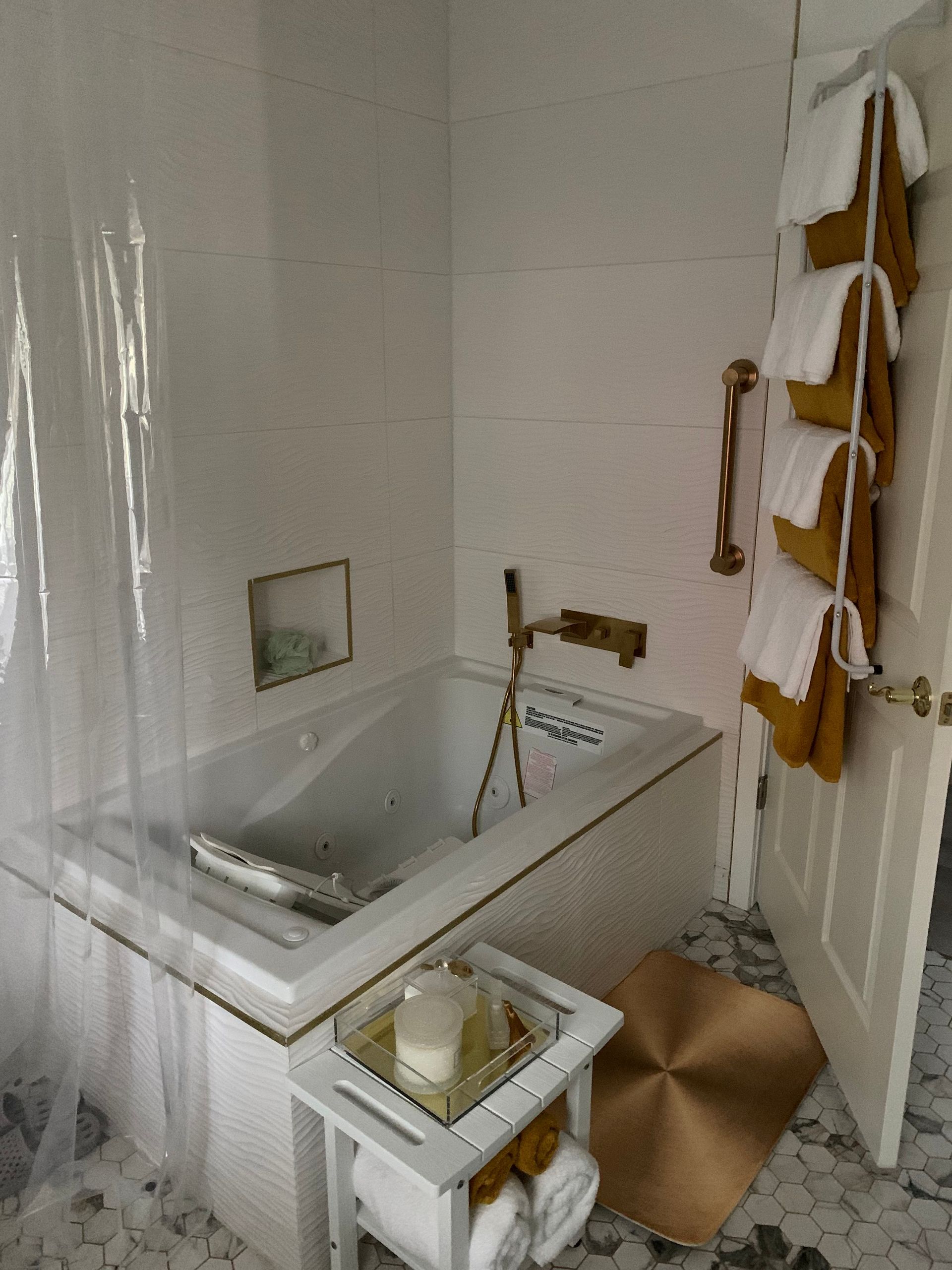 A bathroom with a tub and towels hanging on the wall