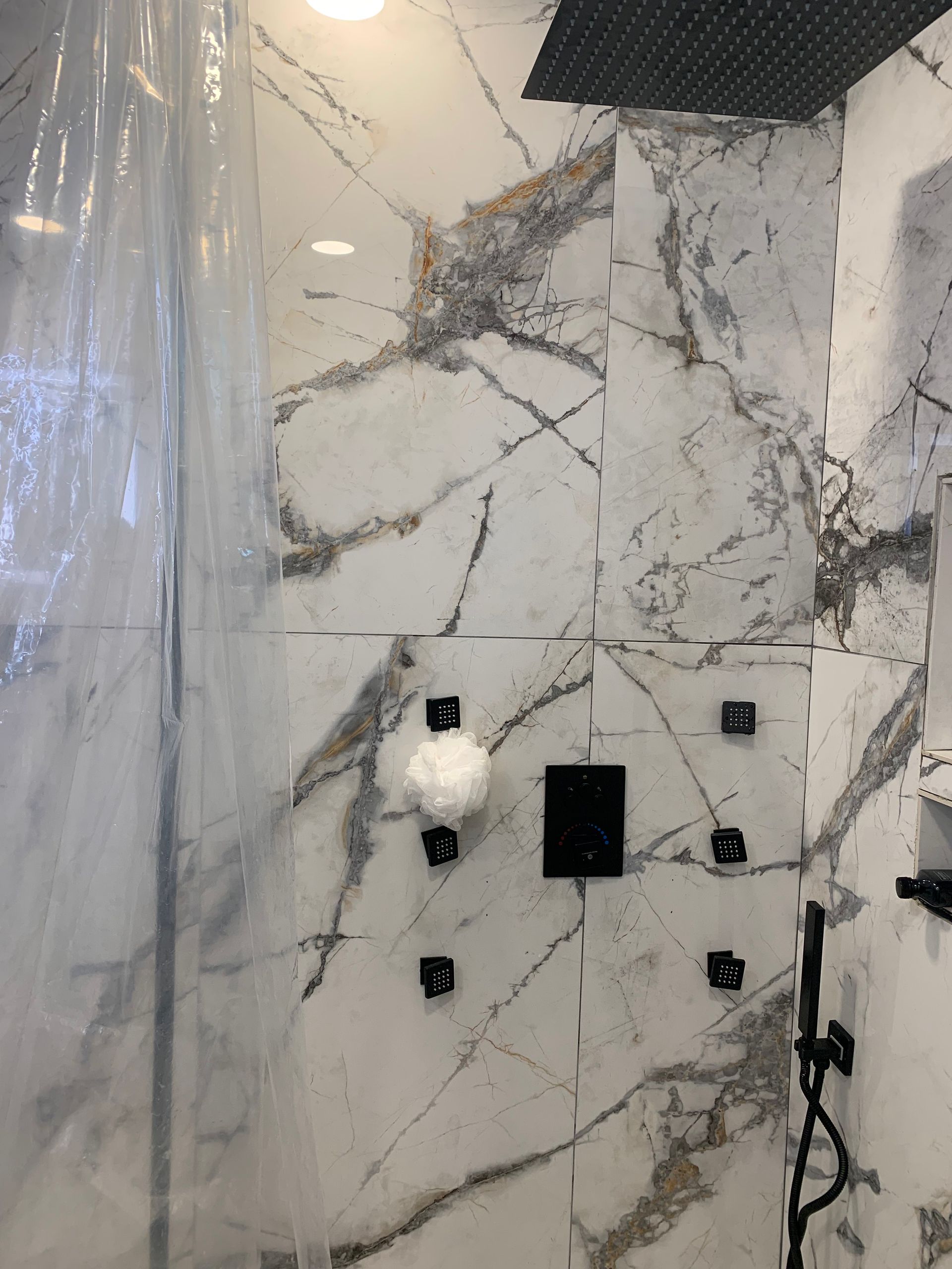 A bathroom with marble tiles and a shower head.