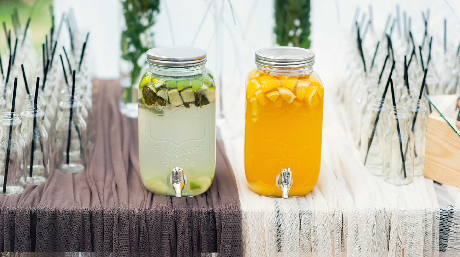 Two jars of drinks are sitting on a wooden table.
