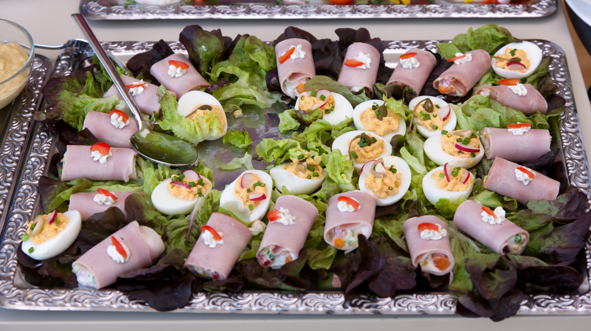 A tray of food with ham , eggs and lettuce on a table.