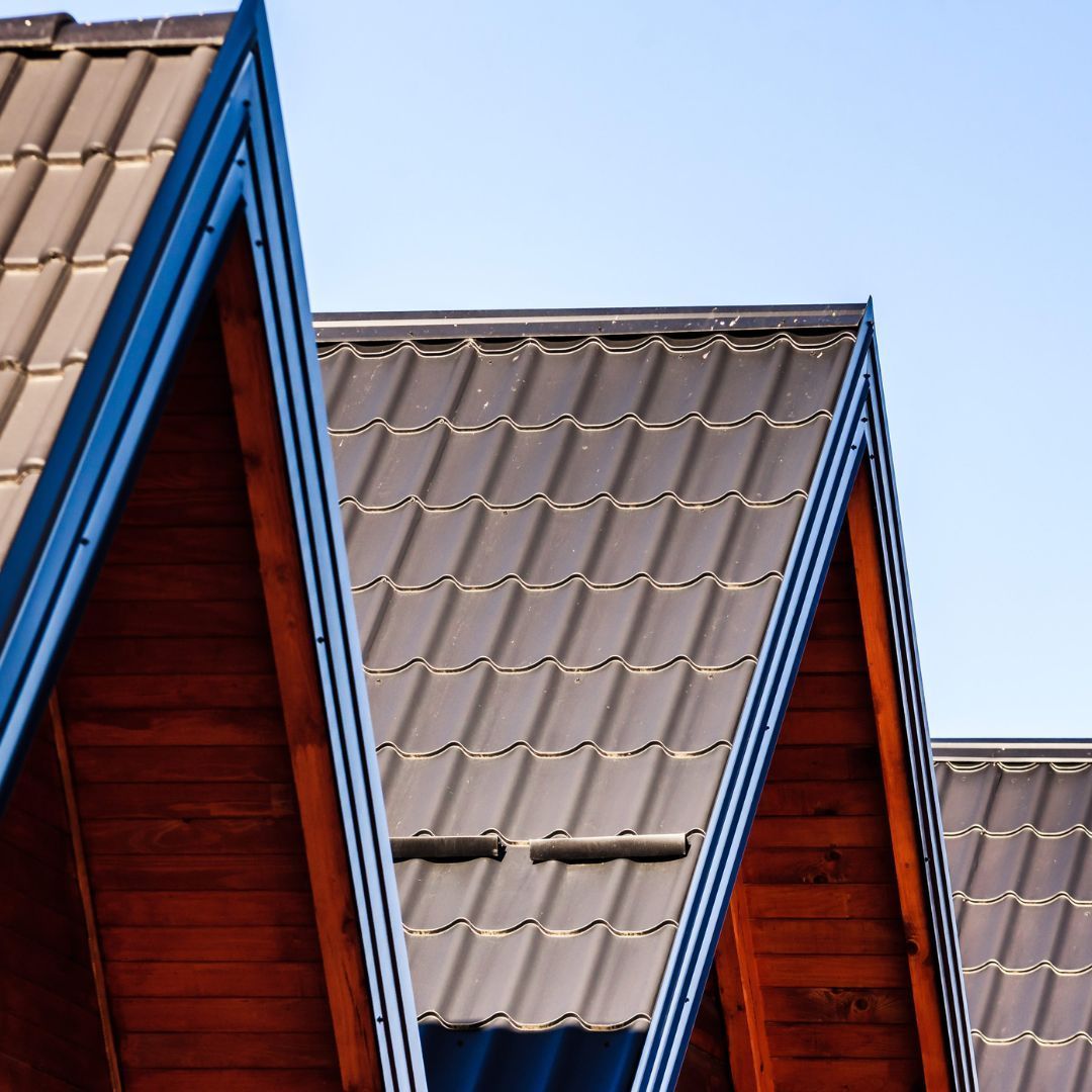 a row of roofs with a blue trim against a blue sky