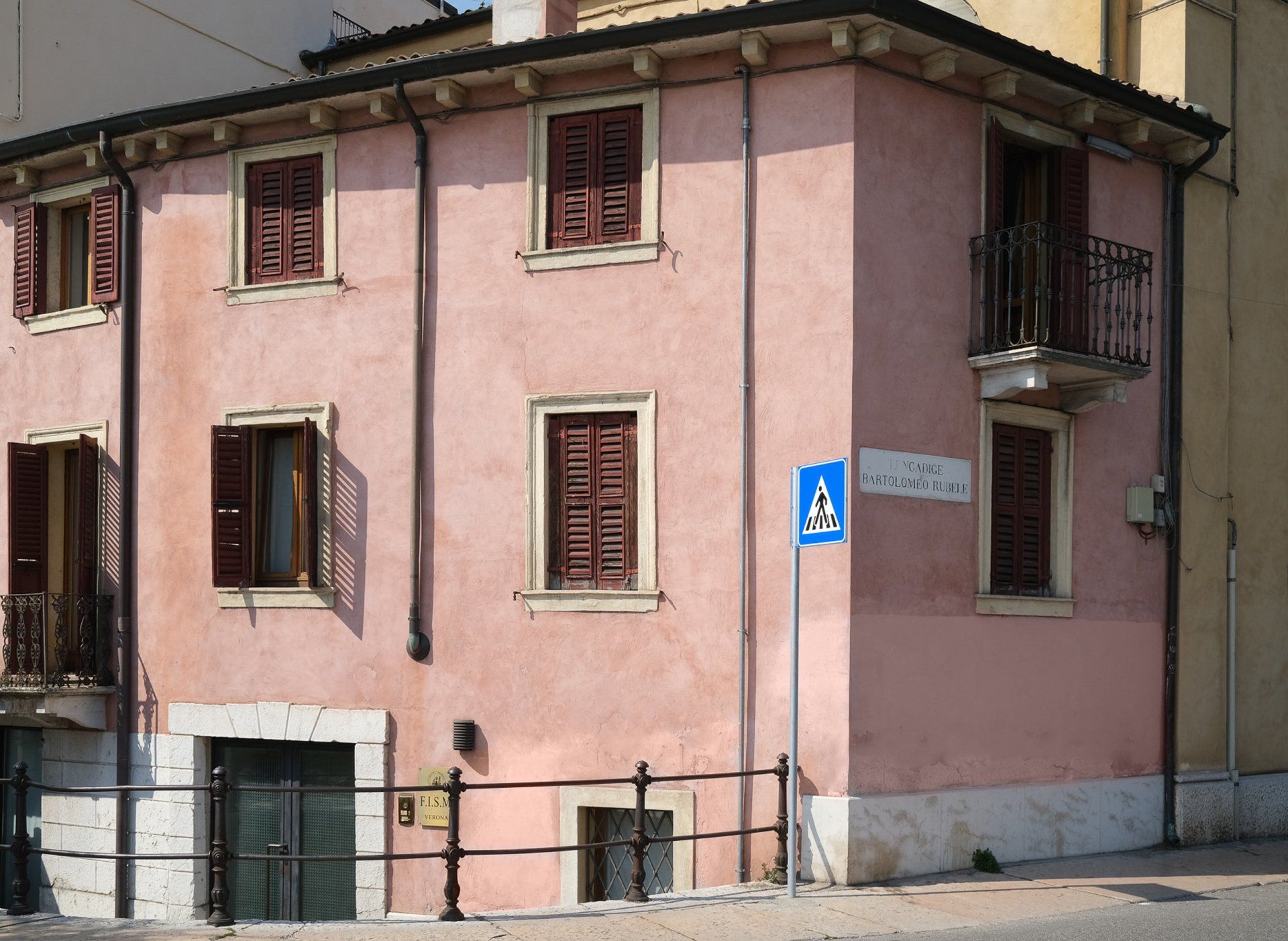Un edificio rosa con un cartello blu con su scritto "a".