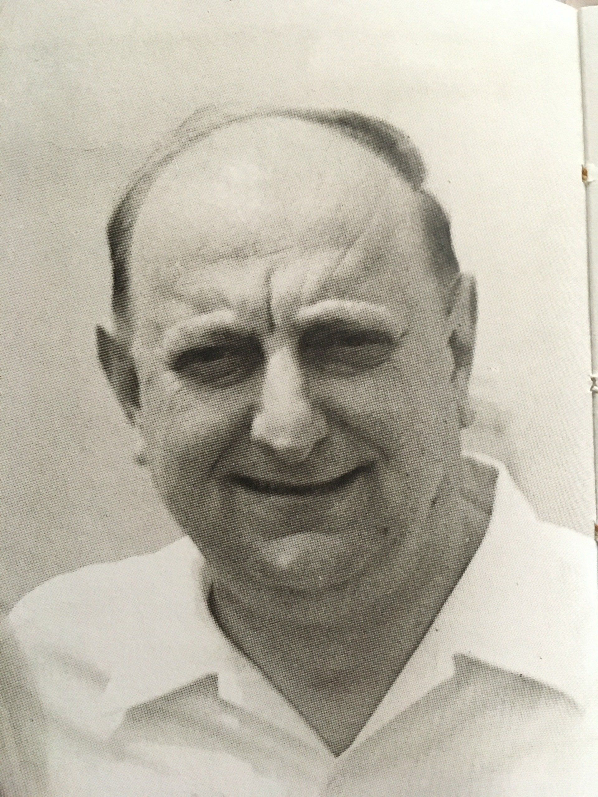 Un uomo con una camicia bianca sorride in una foto in bianco e nero.