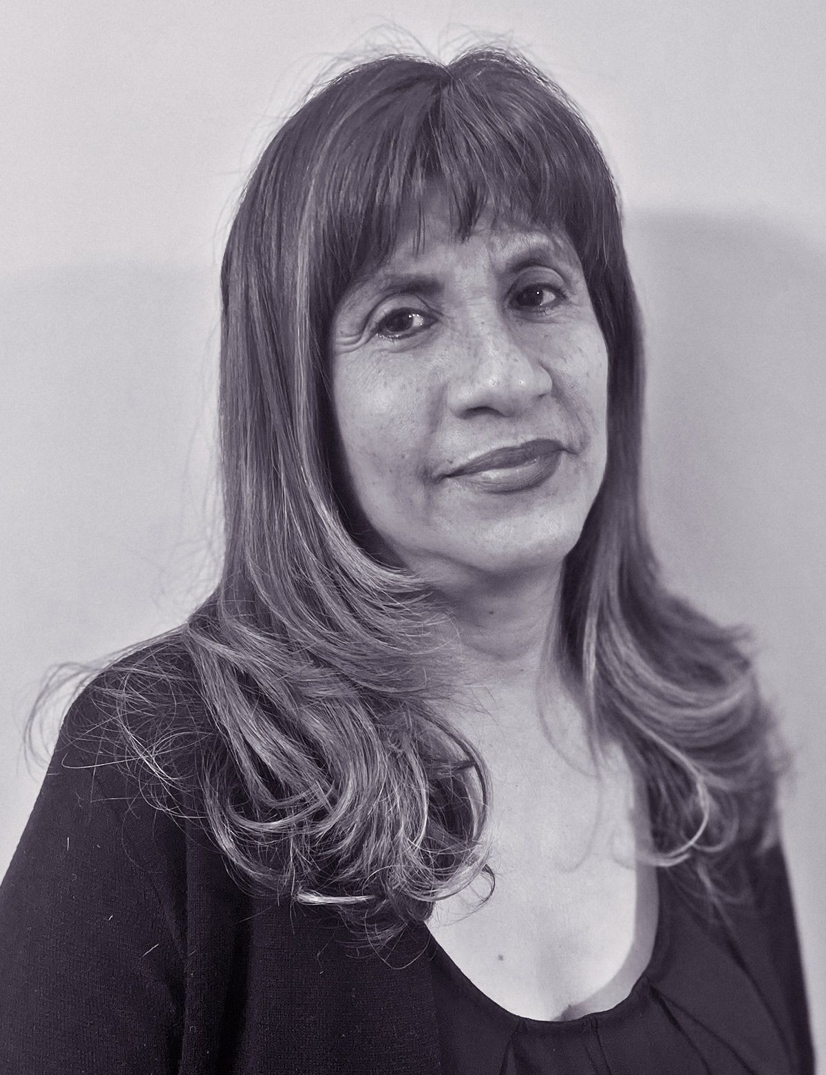 A woman with long straight  hair is  smiling in a black and white photo.