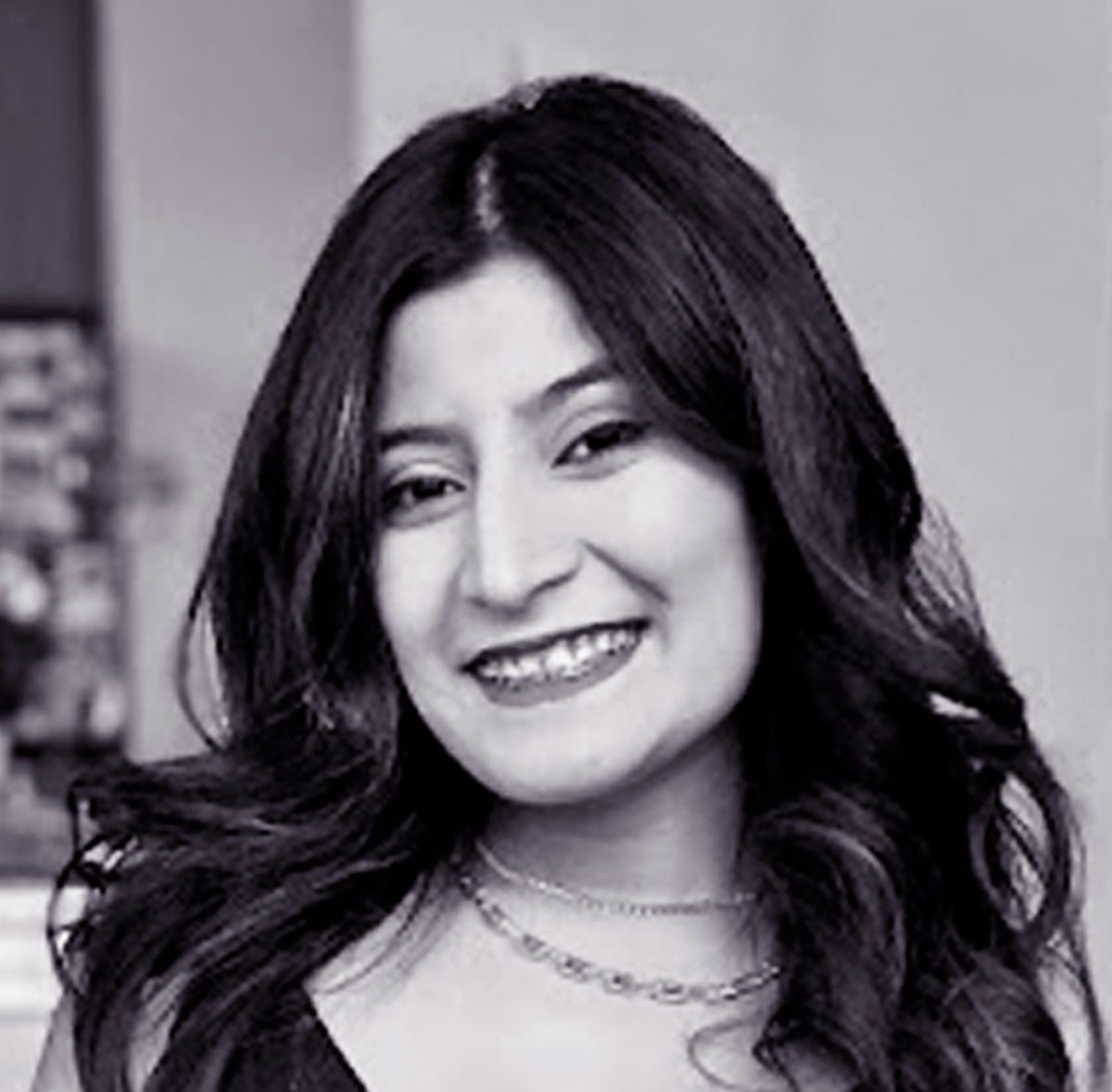 A woman with long straight  hair is  smiling in a black and white photo.