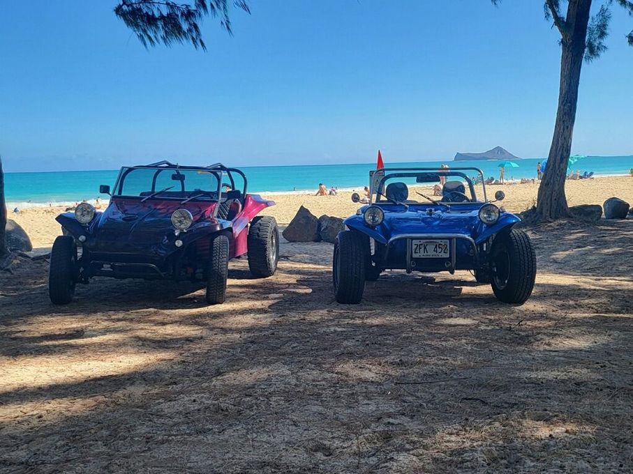 Two buggies are parked next to each other on the beach.