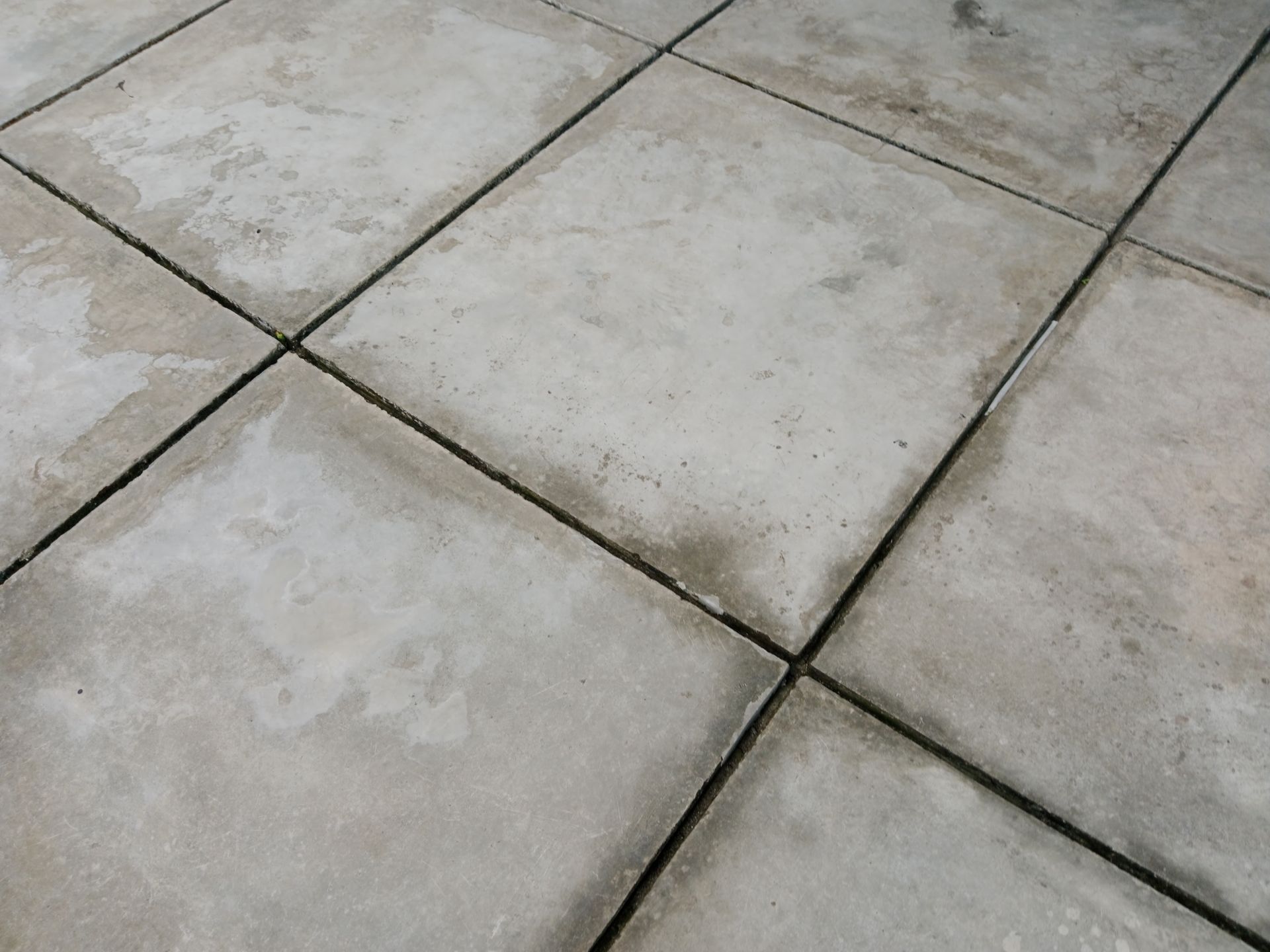 Gray concrete patio tiles with dark grout lines in a diagonal grid pattern