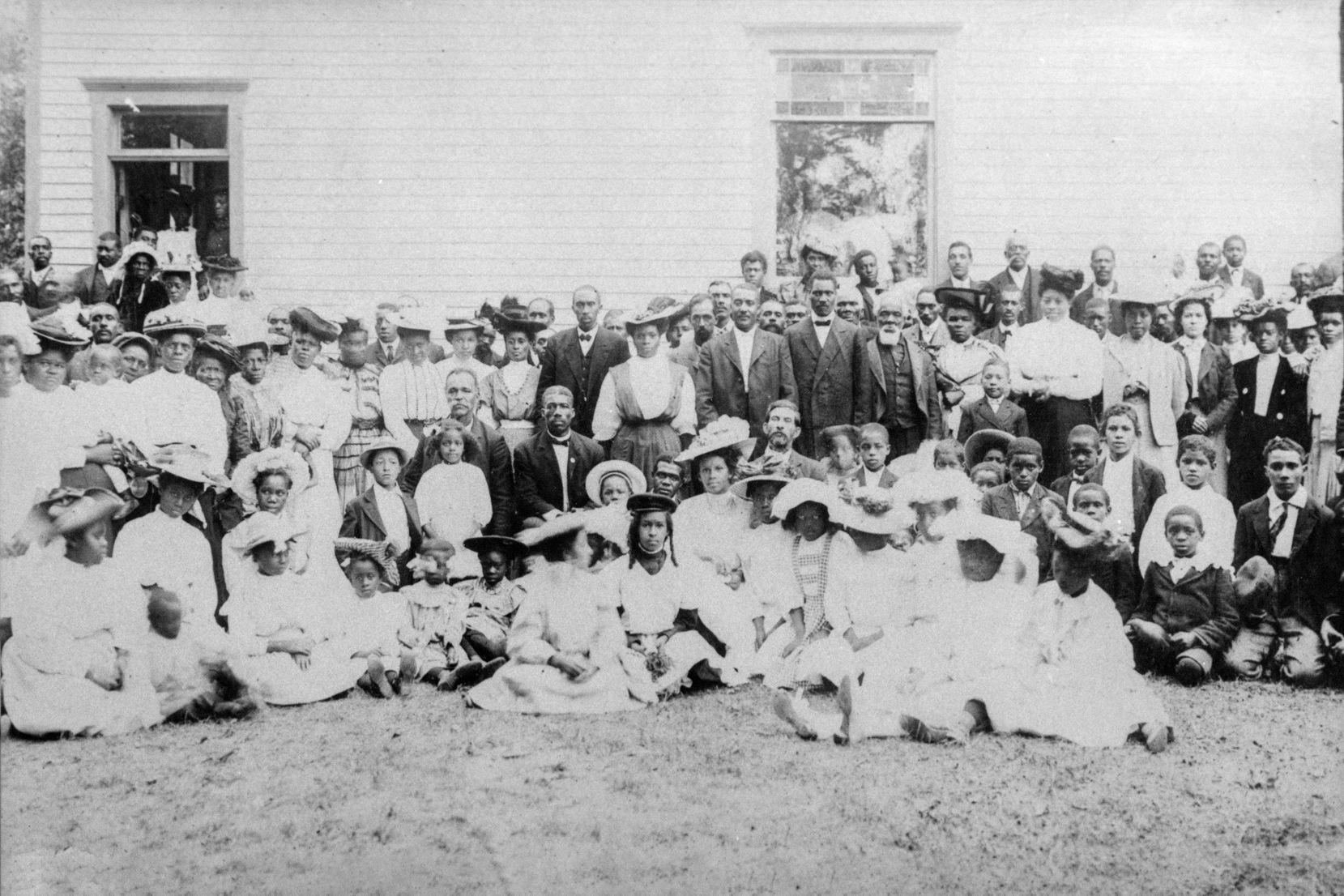 A black and white photo of a large group of church members in front of the church