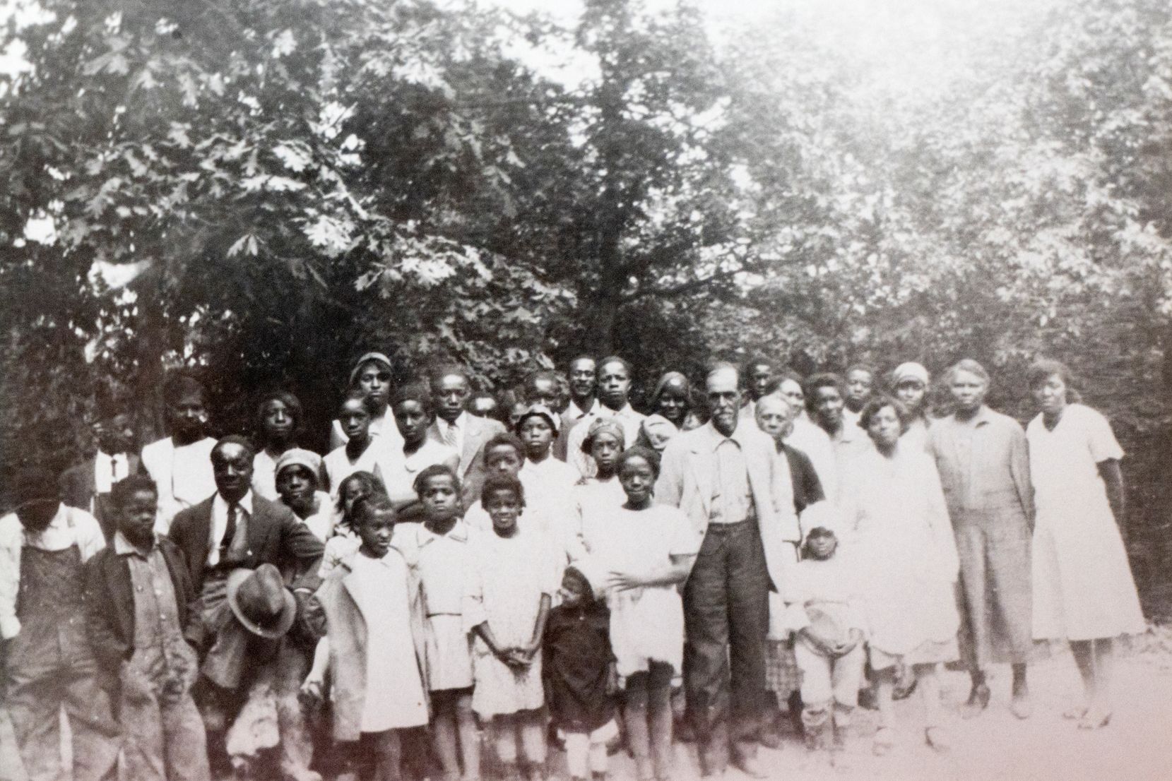 Group of men, women and children - standing on the Log Providence Property with the forest in the background.

