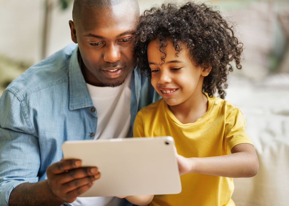 A father looking at a table with his son. 