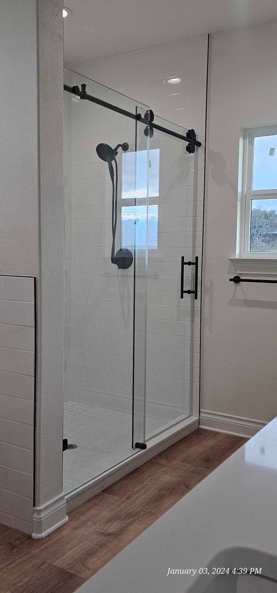 A modern bathroom with a glass shower enclosure and black hardware.