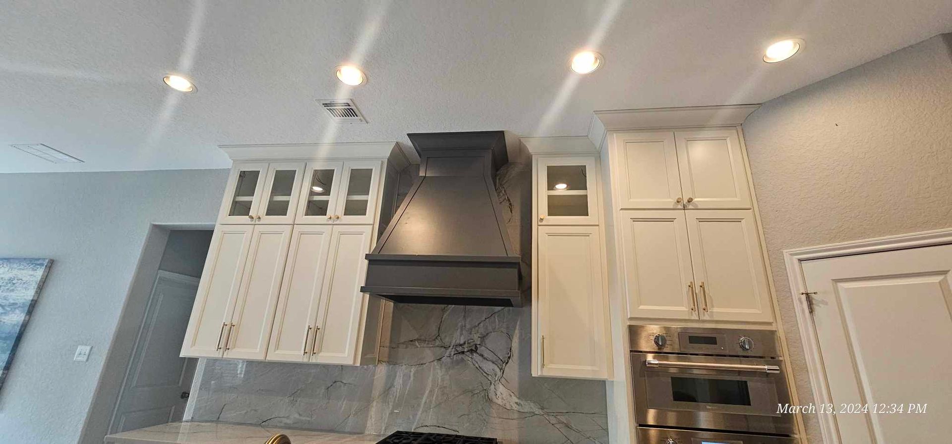 Kitchen with white cabinets, stainless steel appliances, and a dark range hood.