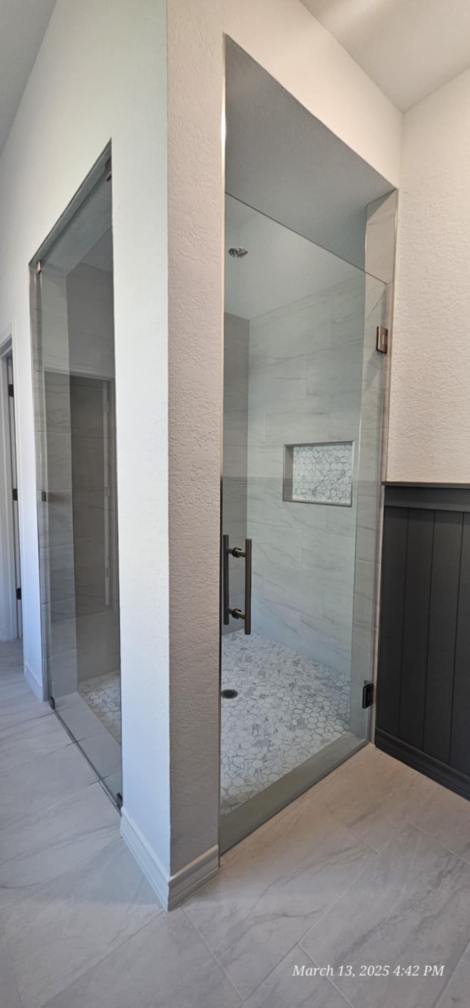 A modern bathroom with a glass shower enclosure and tiled floors.